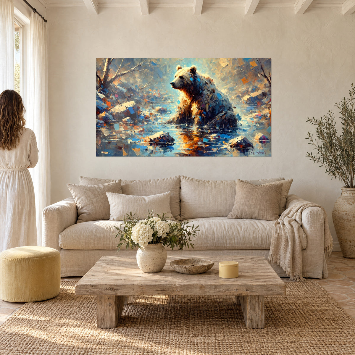Wall art brown bear seated in a blue and ochre river, palette-knife strokes, orange reflections, woman seen from behind, above a sofa in a bright living room