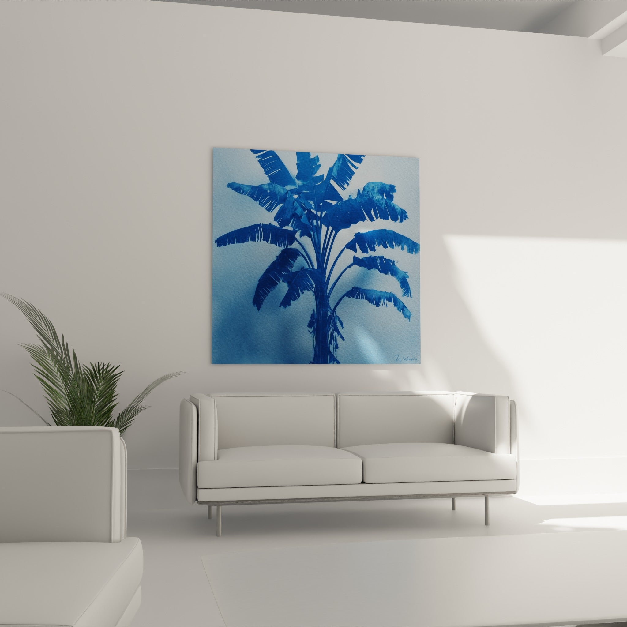 Feuillage tropical bleu marine sur fond bleu pastel, disposé au-dessus d'un canapé dans un salon lumineux