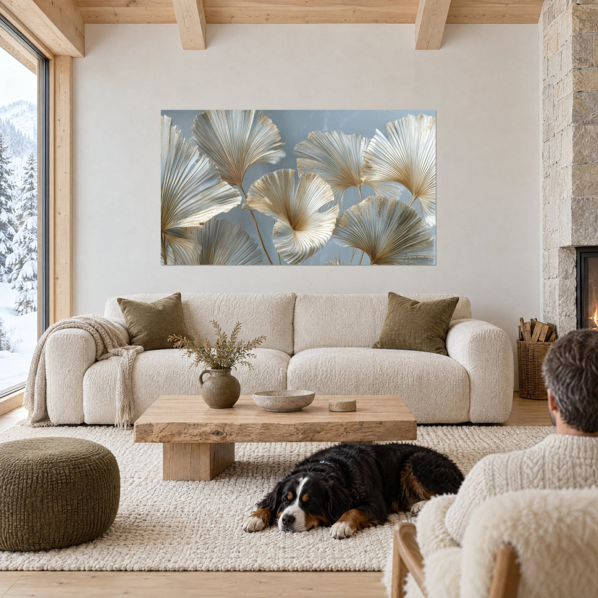 Wall art gilded ginkgo leaves with fine veins on a blue-grey background, black dog lying down, above a sofa in a bright living room
