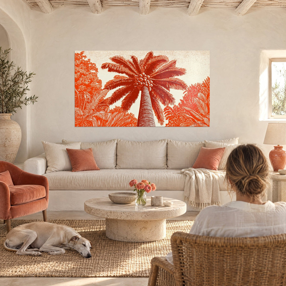 Wall art tropical palm tree in rust and ivory linocut, shot from below, two people seen from behind and a greyhound, above a sofa in a bright living room