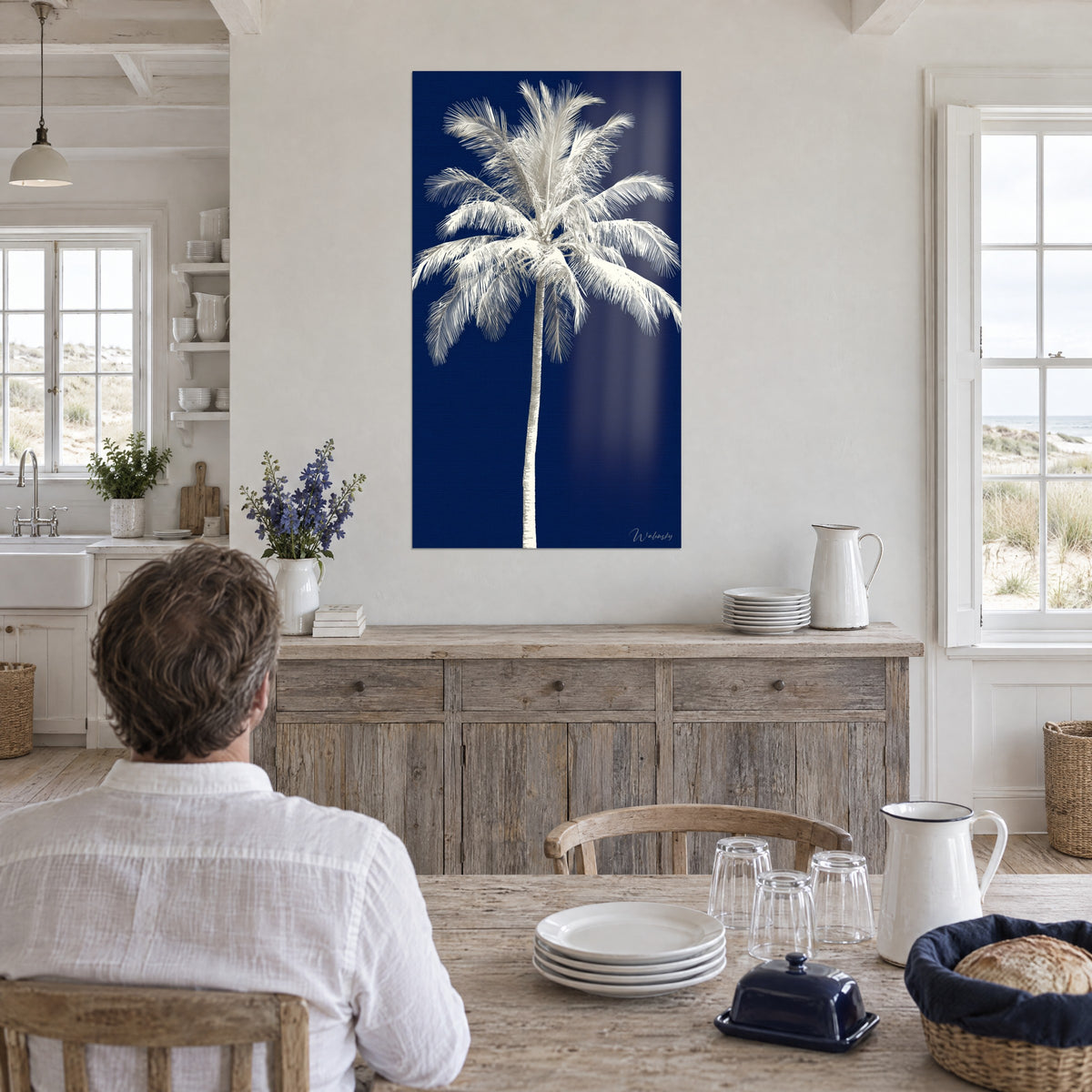 Tableau palme nacrée sur bleu profond, homme de dos attablé, pichet blanc et assiettes, cuisine de bord de mer en bois clair