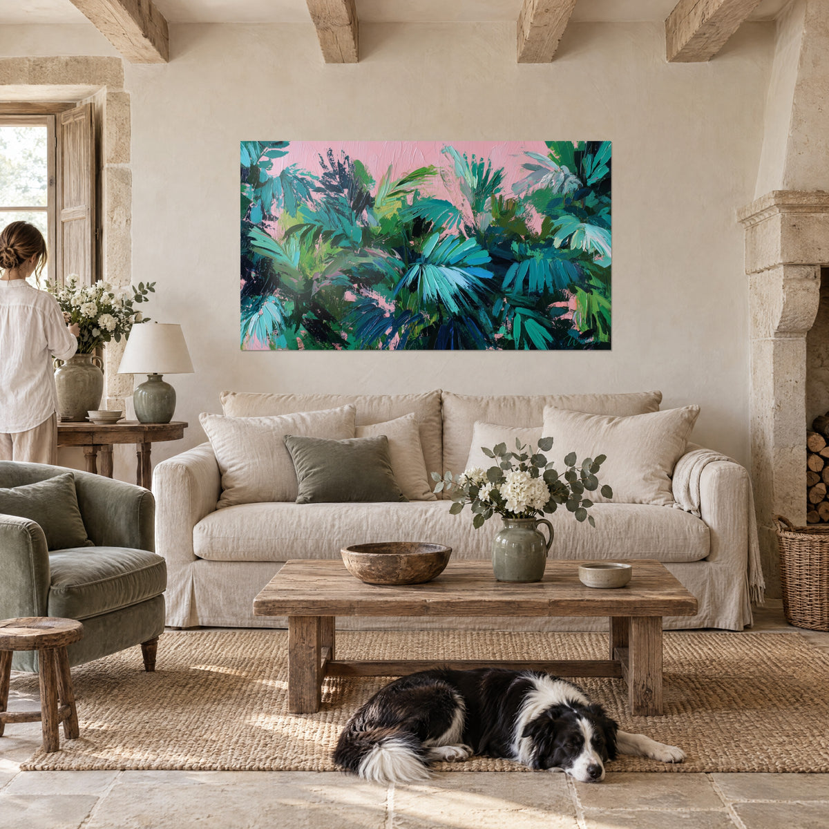 Πίνακας με τυρκουάζ και πράσινα φύλλα φοίνικα σε πουδραρισμένο ροζ φόντο, γυναίκα από την πλάτη και ξαπλωμένος κόλλεϊ, πάνω από έναν καναπέ σε φωτεινό σαλόνι