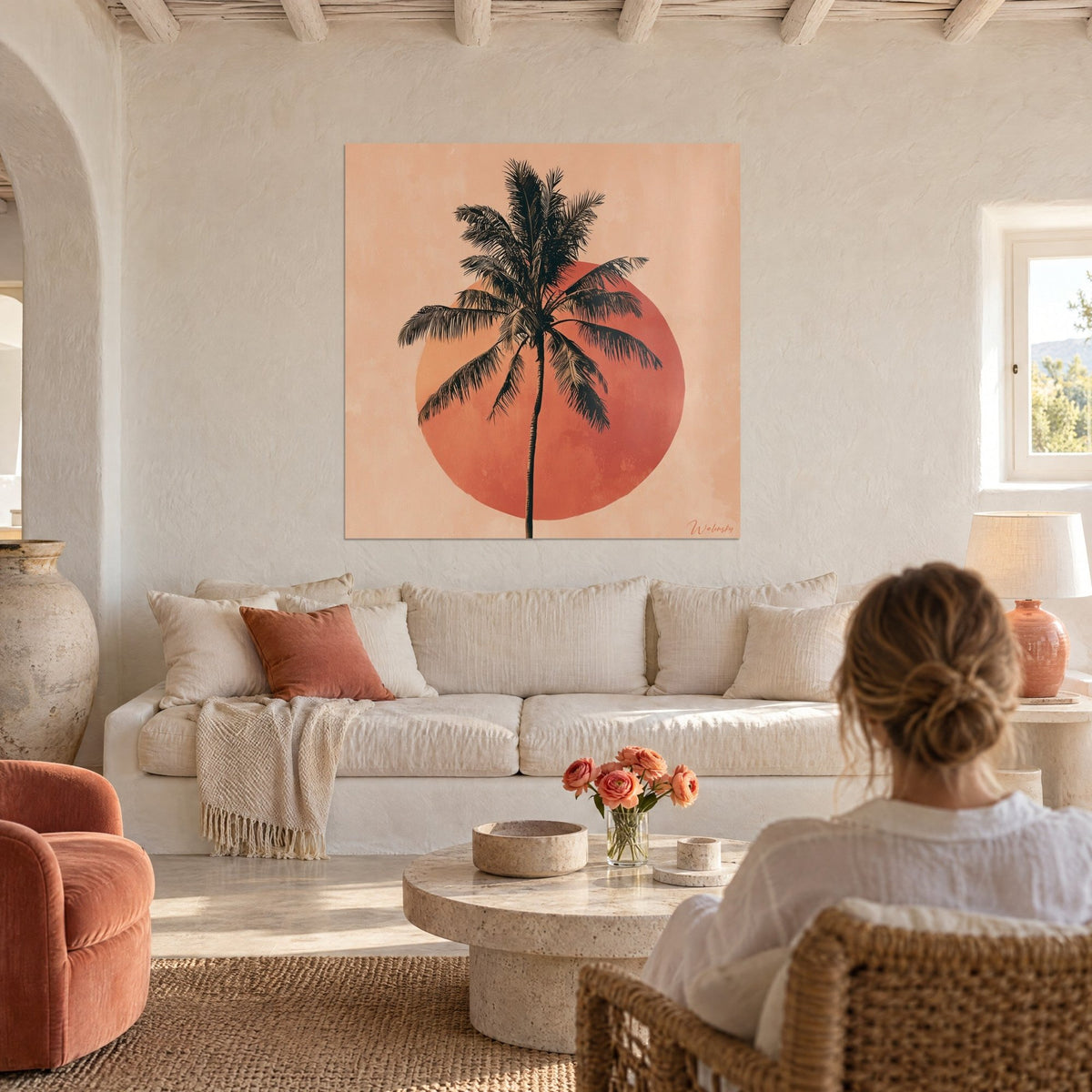 Wall art black palm tree cut out against a terracotta disc, sand pink background, above a sofa in a bright living room