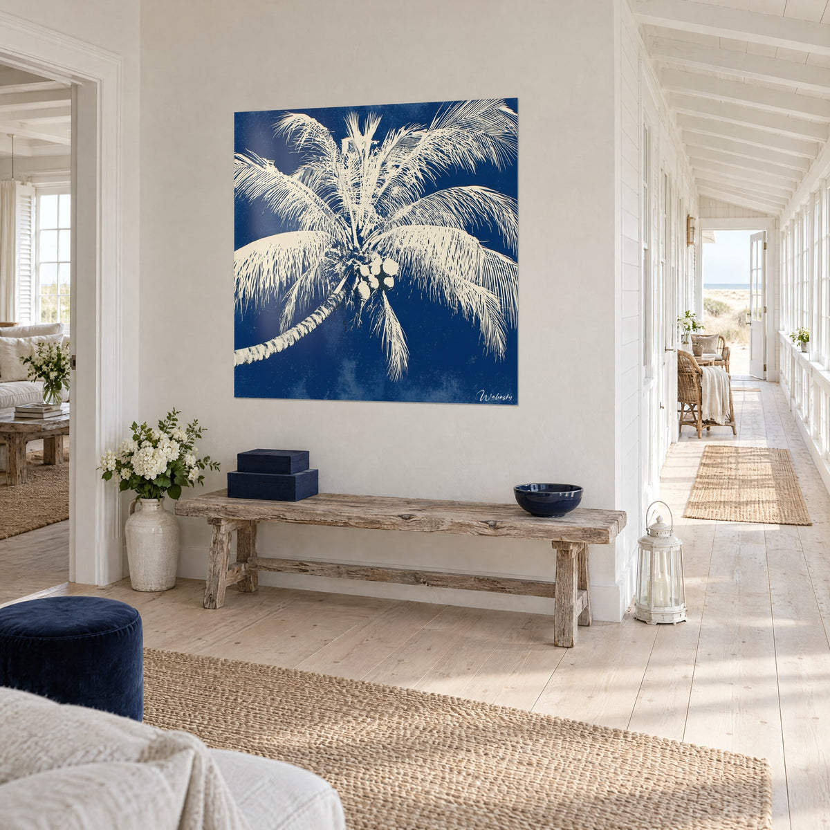 Wall art coconut palm with feathery white fronds on indigo background, facing a blond wood hallway, seaside house