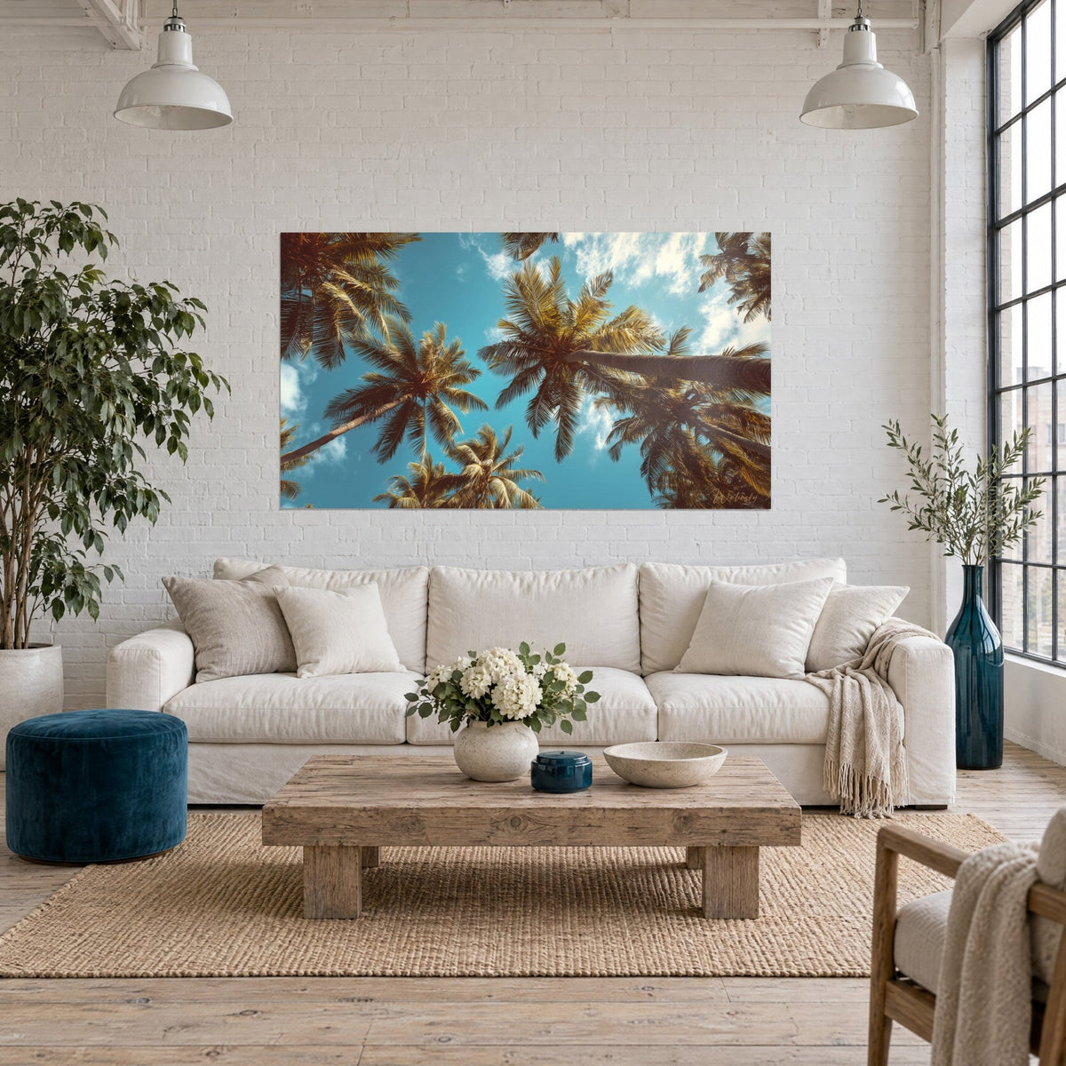 Wall art palm trees shot from a low angle against a turquoise sky, golden brown fronds, above a sofa in a bright living room
