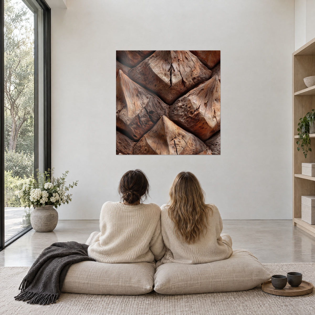 Gemälde Mosaik aus Zimtbraunen und sandfarbenen Schuppen, getüpfeltes Relief, zwei Frauen im cremefarbenen Pullover sitzen von hinten vor dem Bild