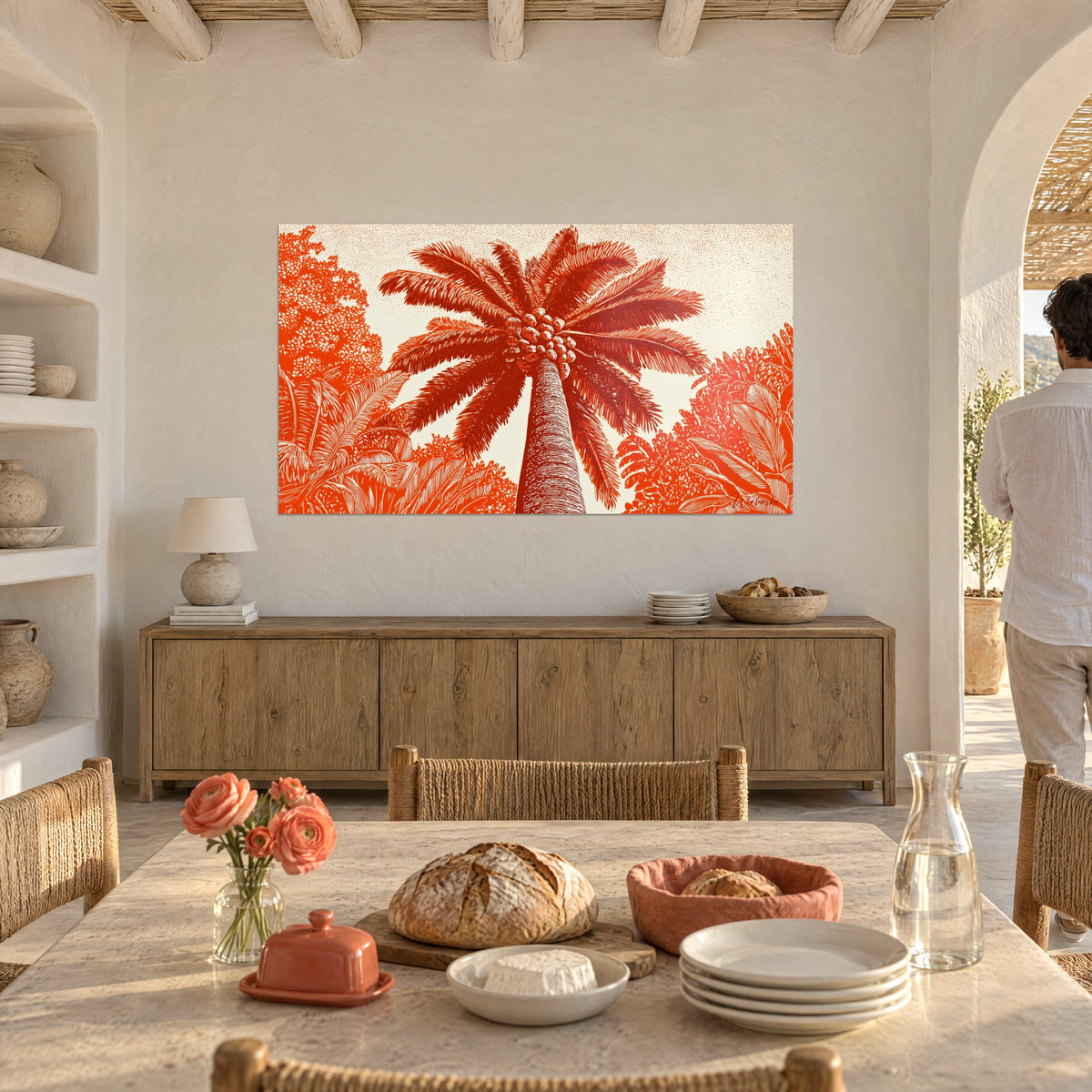 Tableau feuillage de palmier brun-rouge et orange sur fond crème, une silhouette de dos près d'une arche, table dressée avec pain et pivoines, salon méditerranéen