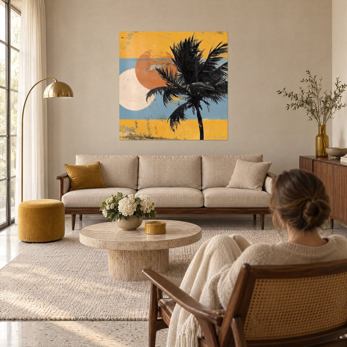 Wall art black palm with slender fronds in front of an orange sun disc and a cream circle on blue and yellow tones, above a sofa in a bright living room