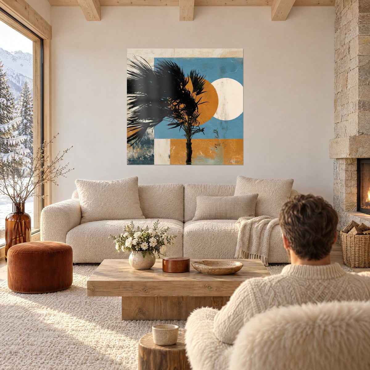 Wall art black palm with tousled fronds in front of an ochre disc and a cream circle on blue background, above a sofa in a bright living room