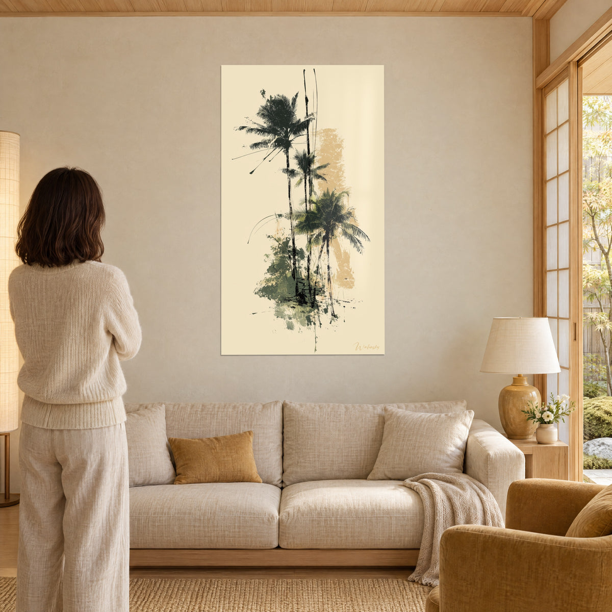 Tableau palmiers d'encre vert olive sur fond beige sable, troncs fins et frondes éclaboussées, une femme de dos au-dessus d'un canapé dans un salon lumineux