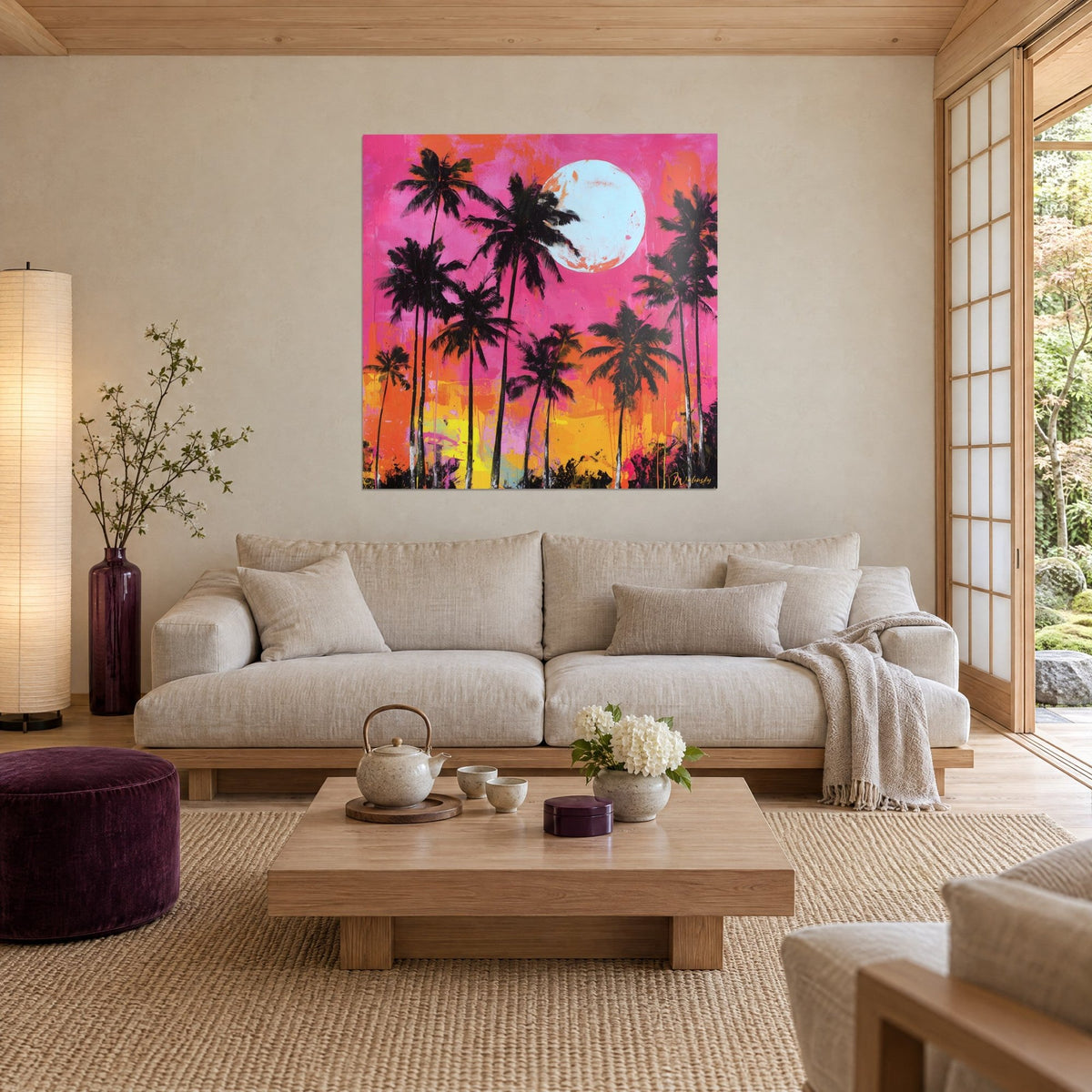 Gemälde schlanke schwarze Palmen vor fuchsiapinkem Himmel, hellblauer Mond und orangefarbener Boden, über einem Sofa in einem hellen Wohnzimmer