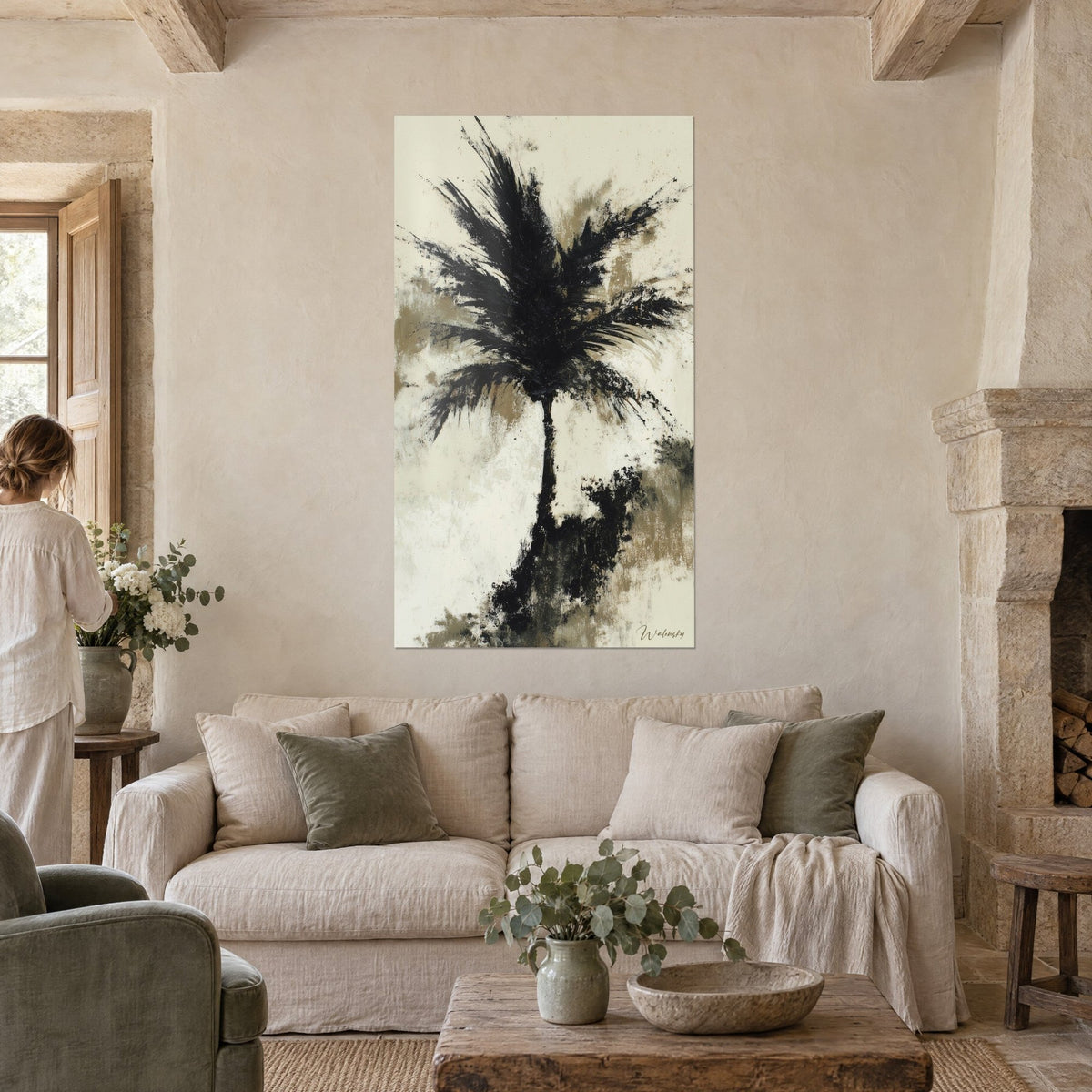 Wall art black palm with ink splashed fronds on cream and beige background, person seen from behind, above a sofa in a bright living room