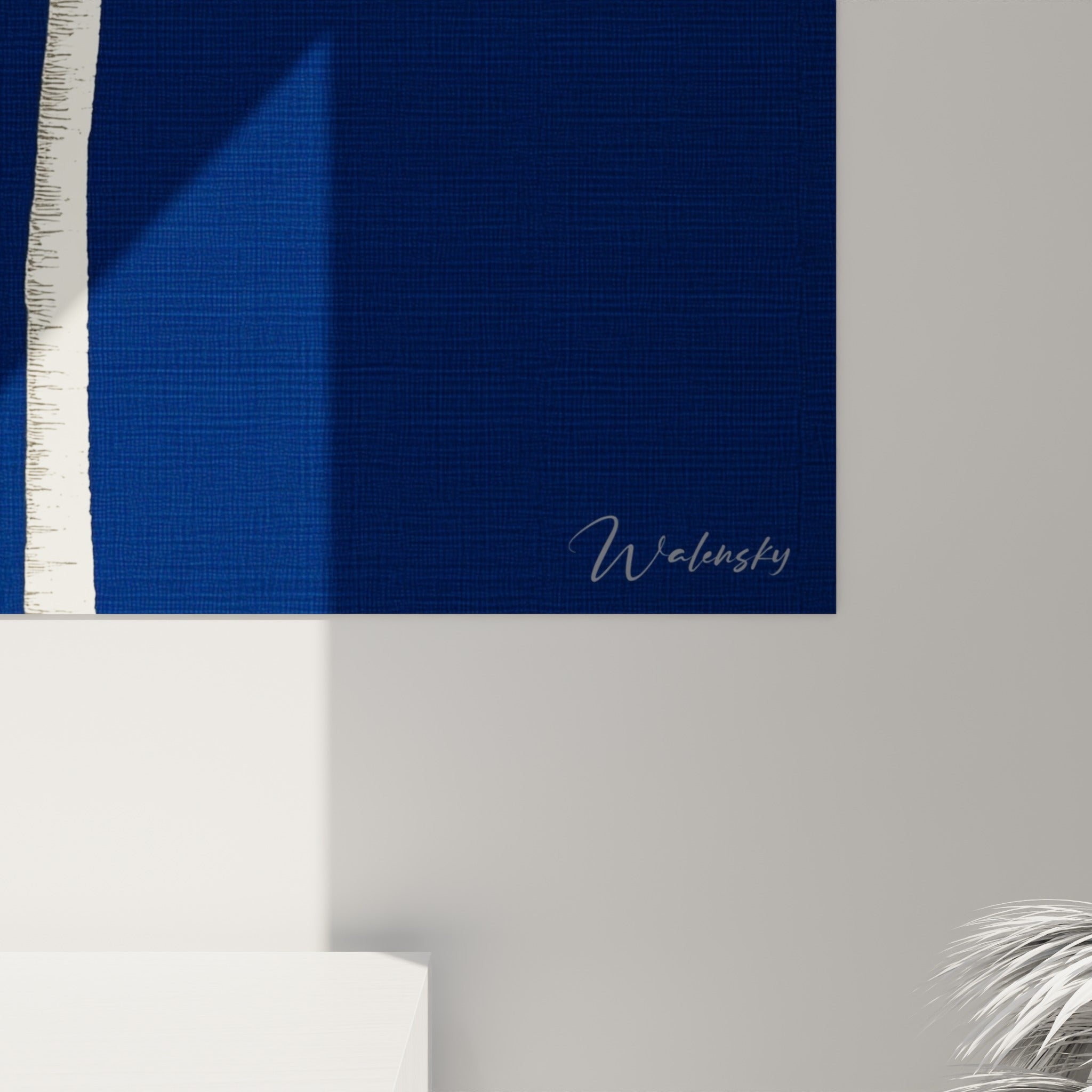 Grain satiné du fond bleu marine et finesse des palmes blanches peintes, visibles en gros plan sur l'œuvre encadrée