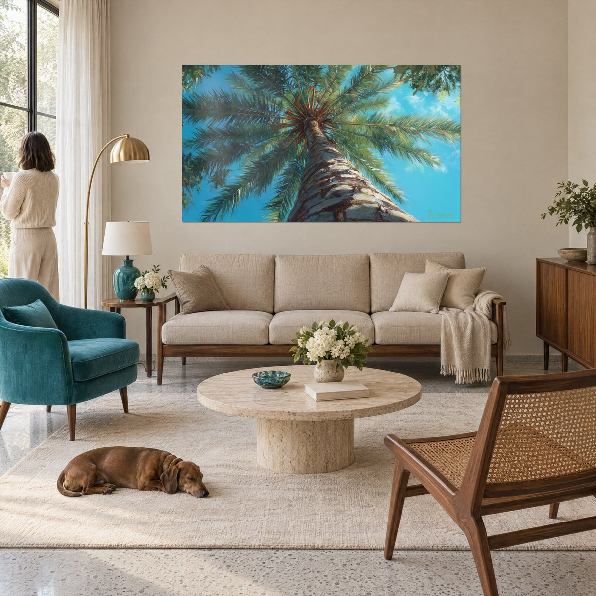 Wall art palm tree seen from below, striated brown trunk and sage green fronds against a turquoise sky, above a sofa in a bright living room