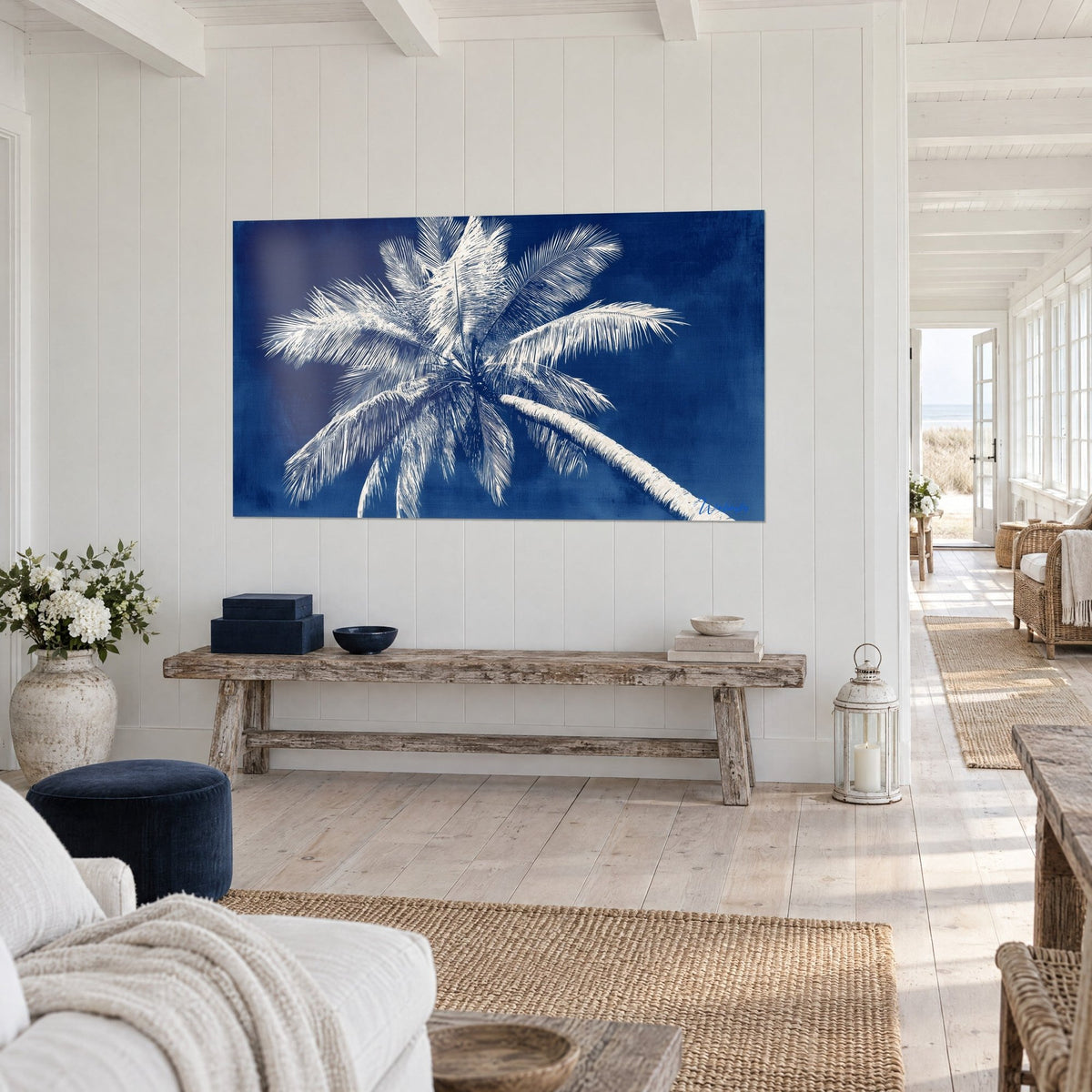 Wall art leaning coconut palm with ivory fronds on an indigo background, blond wood and jute, three-quarter view in a bright hallway
