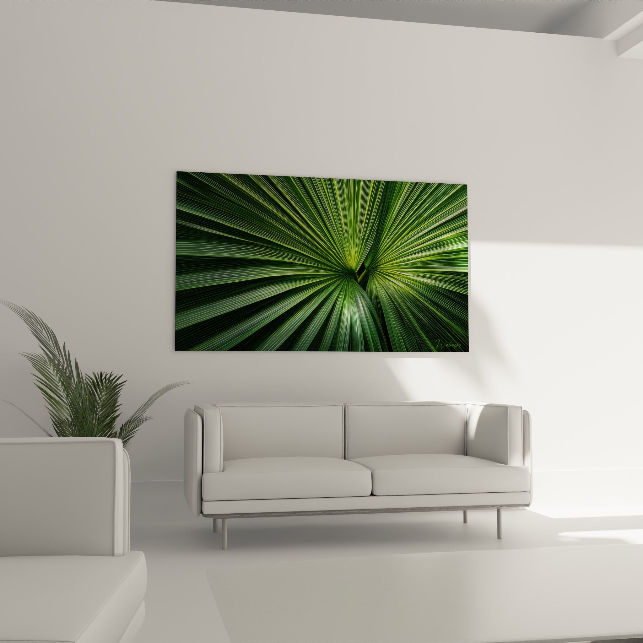 Éventail végétal vert olive et émeraude, disposé au-dessus d'un canapé dans un salon lumineux