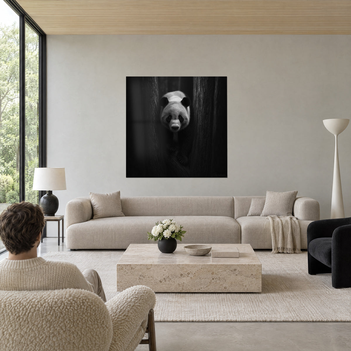 Cuadro panda gigante que surge entre dos troncos negros, pelaje blanco y negro, sobre un sofá en un salón luminoso
