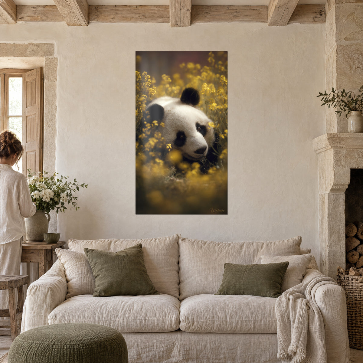 Gemälde Panda in Elfenbein und Schwarz, zwischen gelben Rapsblüten zusammengekauert, von einer Frau von hinten über einem Sofa in einem hellen Wohnzimmer betrachtet