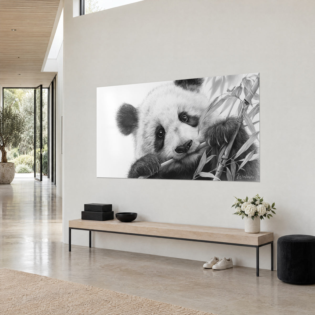 Πίνακας ενός γιγάντιου panda σε ασπρόμαυρα χρώματα, σκούρο ρύγχος δίπλα στο μπαμπού, γκρίζα λεπτά φύλλα, κρεμ τοίχος και ανοιχτόχρωμο ξύλινο παγκάκι