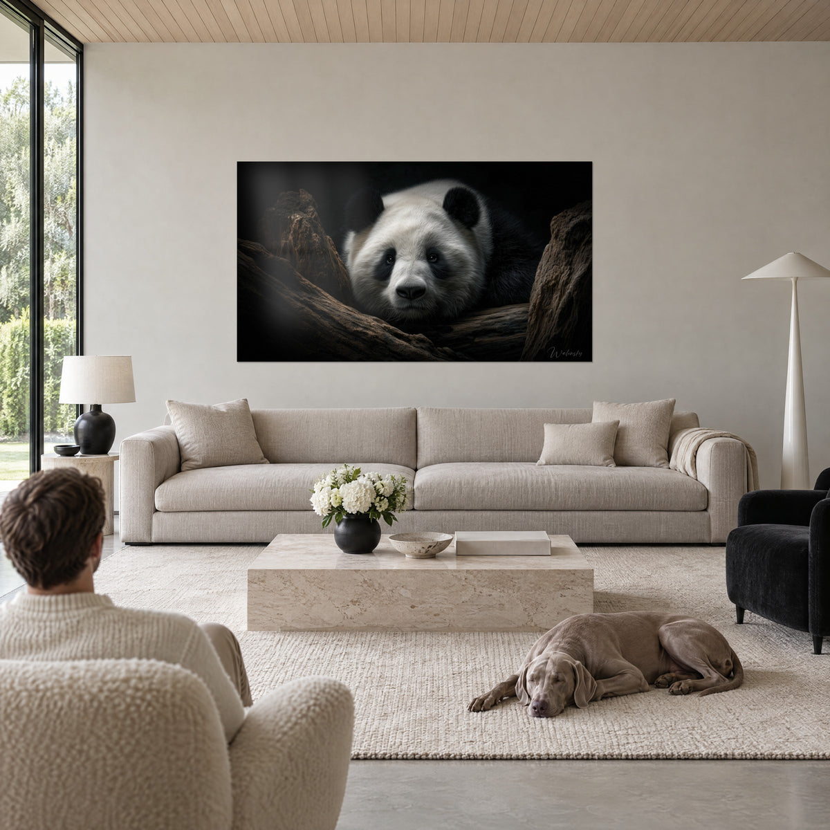 Obraz gigantyczna panda o kości słoniowej sierści i czarnych uszach, wciśnięta między dwa brązowe pnie, nad kanapą w jasnym salonie