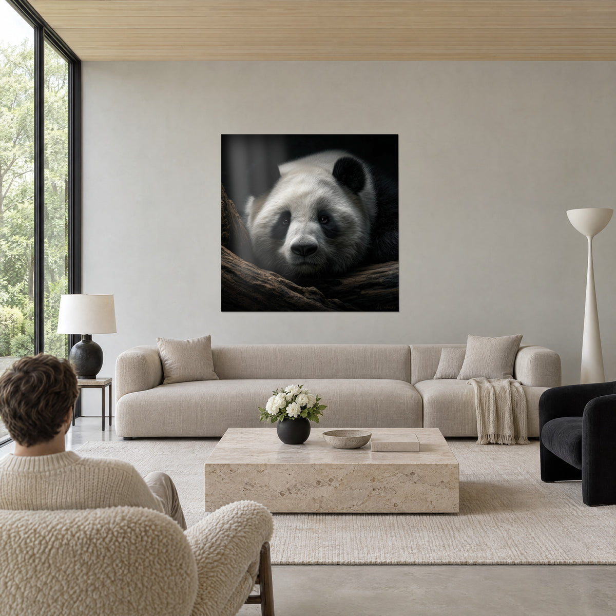Quadro panda gigante dal pelo avorio e orecchie nere, muso appoggiato su un ramo marrone, sopra un divano in un soggiorno luminoso