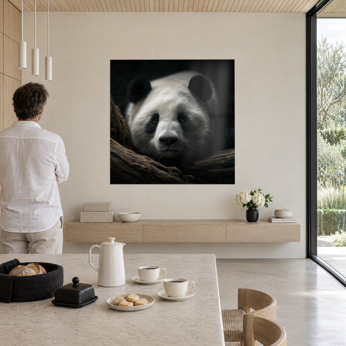 Quadro ritratto di panda gigante dallo sguardo dolce, pelliccia bianco sporco e nero profondo, osservato da un uomo in camicia chiara in un salotto
