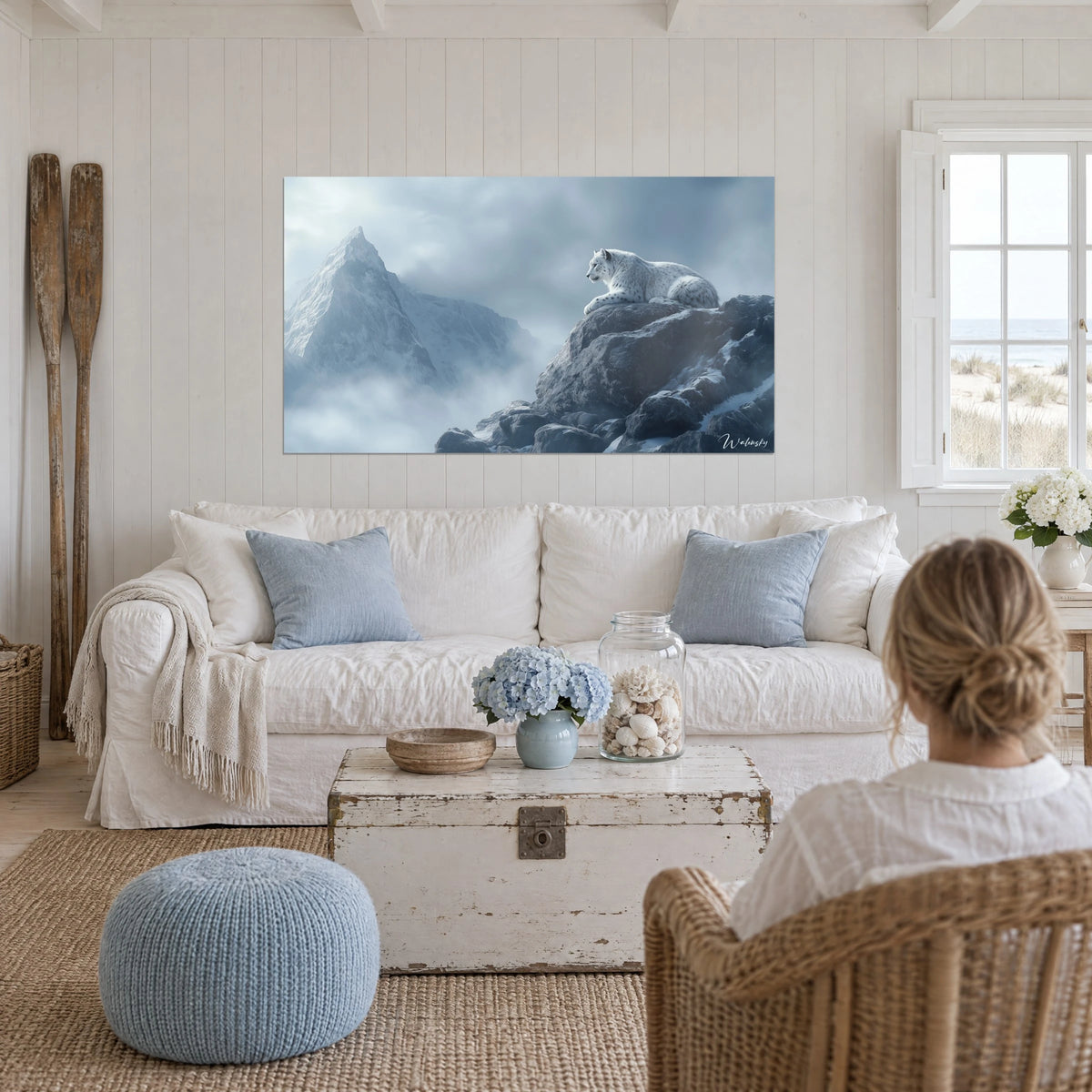 Tableau panthère des neiges blanche tachetée couchée sur un rocher gris-bleu, brume glacée, au-dessus d'un canapé dans un salon lumineux