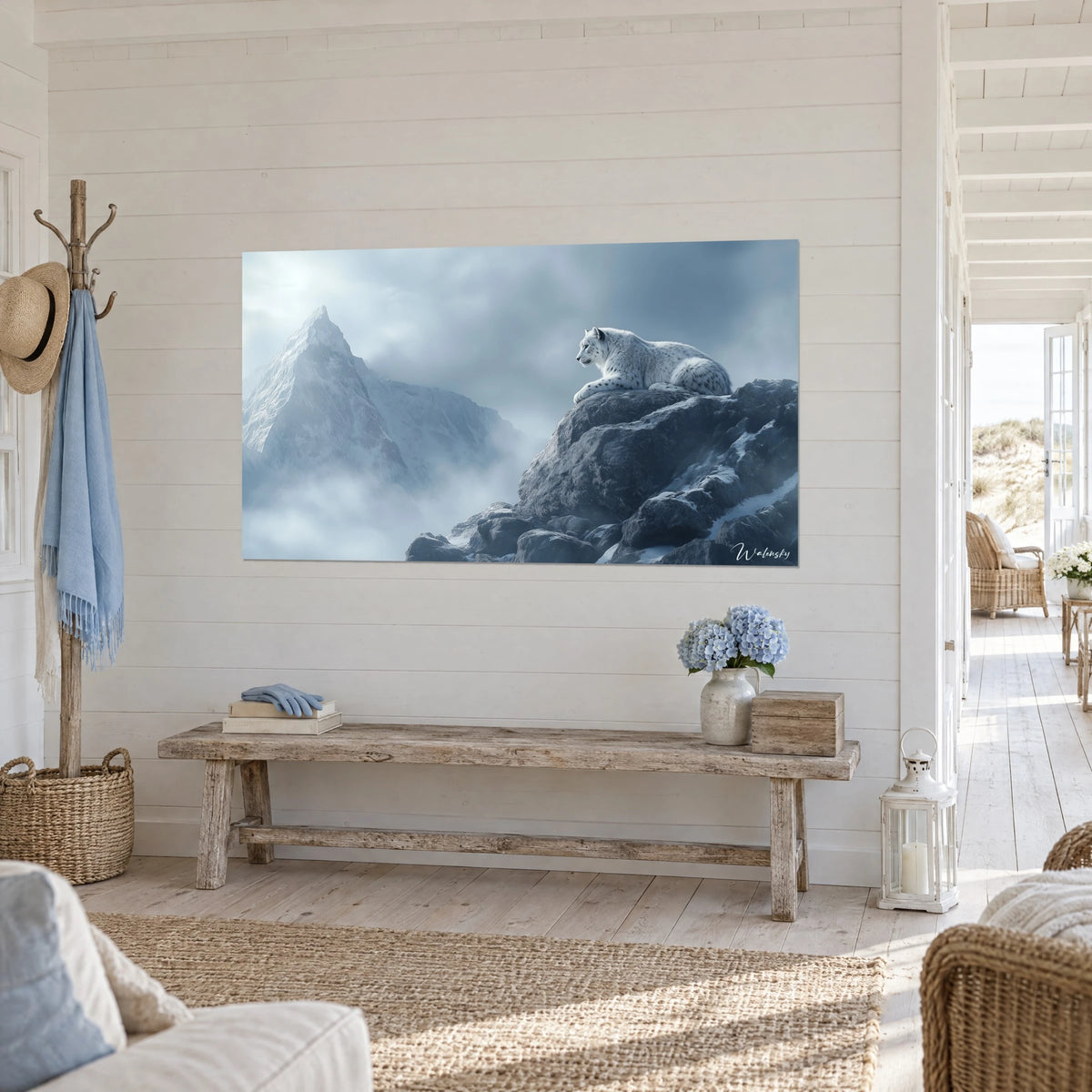 Cuadro de un felino inmaculado que acecha una cima nevada, piedras oscuras de pizarra y cielo azul acero, en la entrada de una casa junto al mar