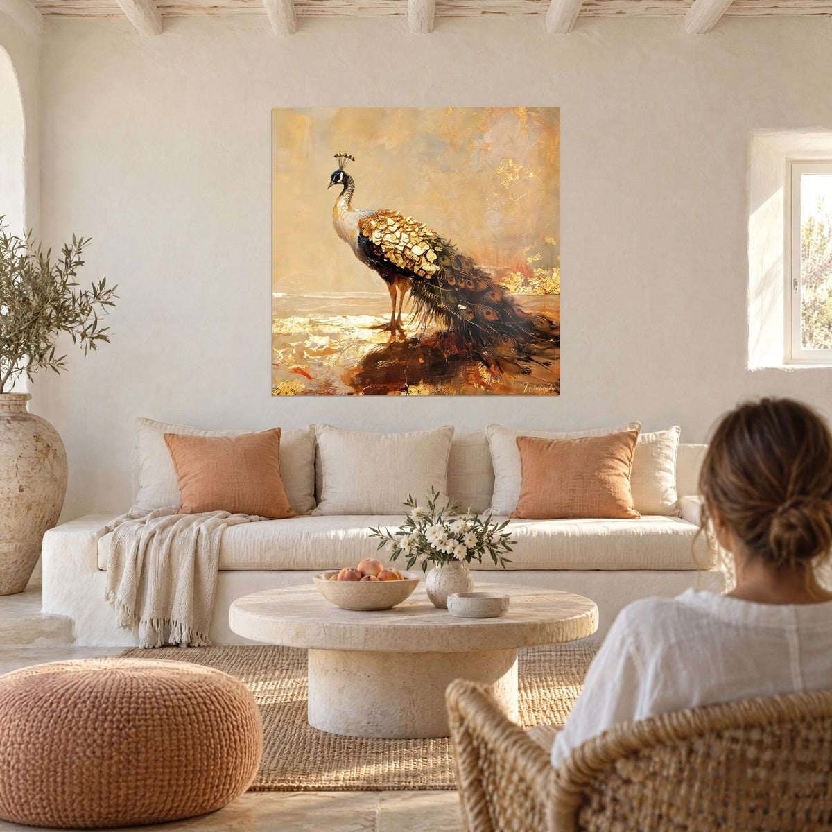 Tableau paon aux plumes d'or craquelées, fond ocre et abricot, une femme de dos, au-dessus d'un canapé dans un salon lumineux