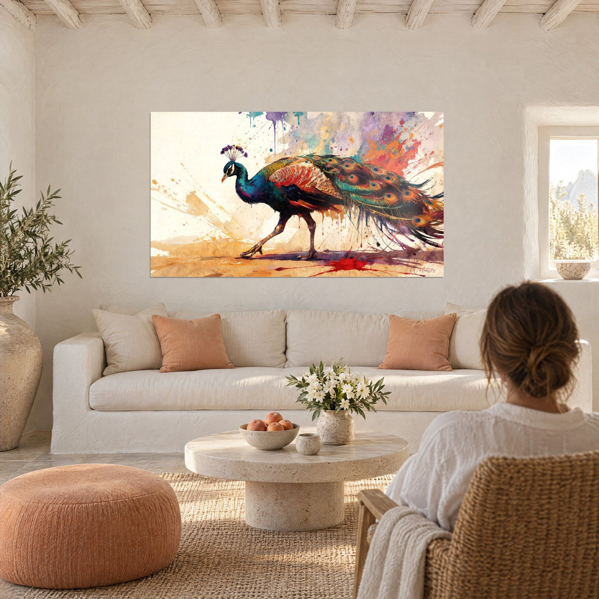 Gemälde Pfau in Blau mit ockerfarbenen Federn und violetten Spritzern, eine Frau von hinten, über einem Sofa in einem hellen Wohnzimmer
