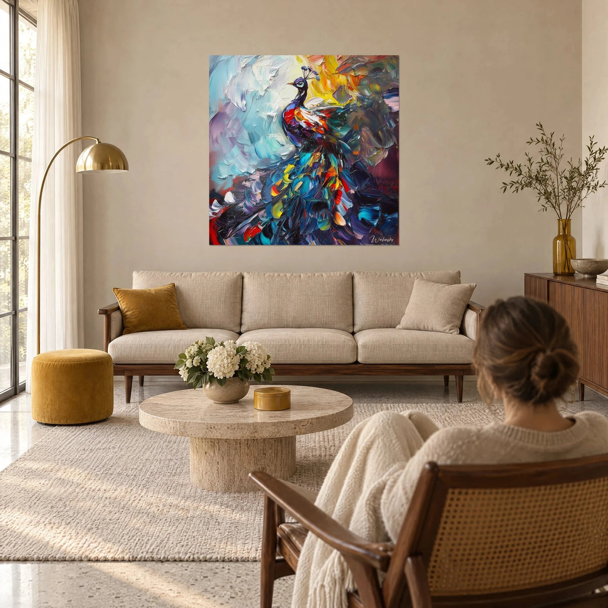 Tableau paon aux plumes bleu nuit et rouge vif, fond turquoise pâle, une femme de dos au-dessus d'un canapé dans un salon lumineux