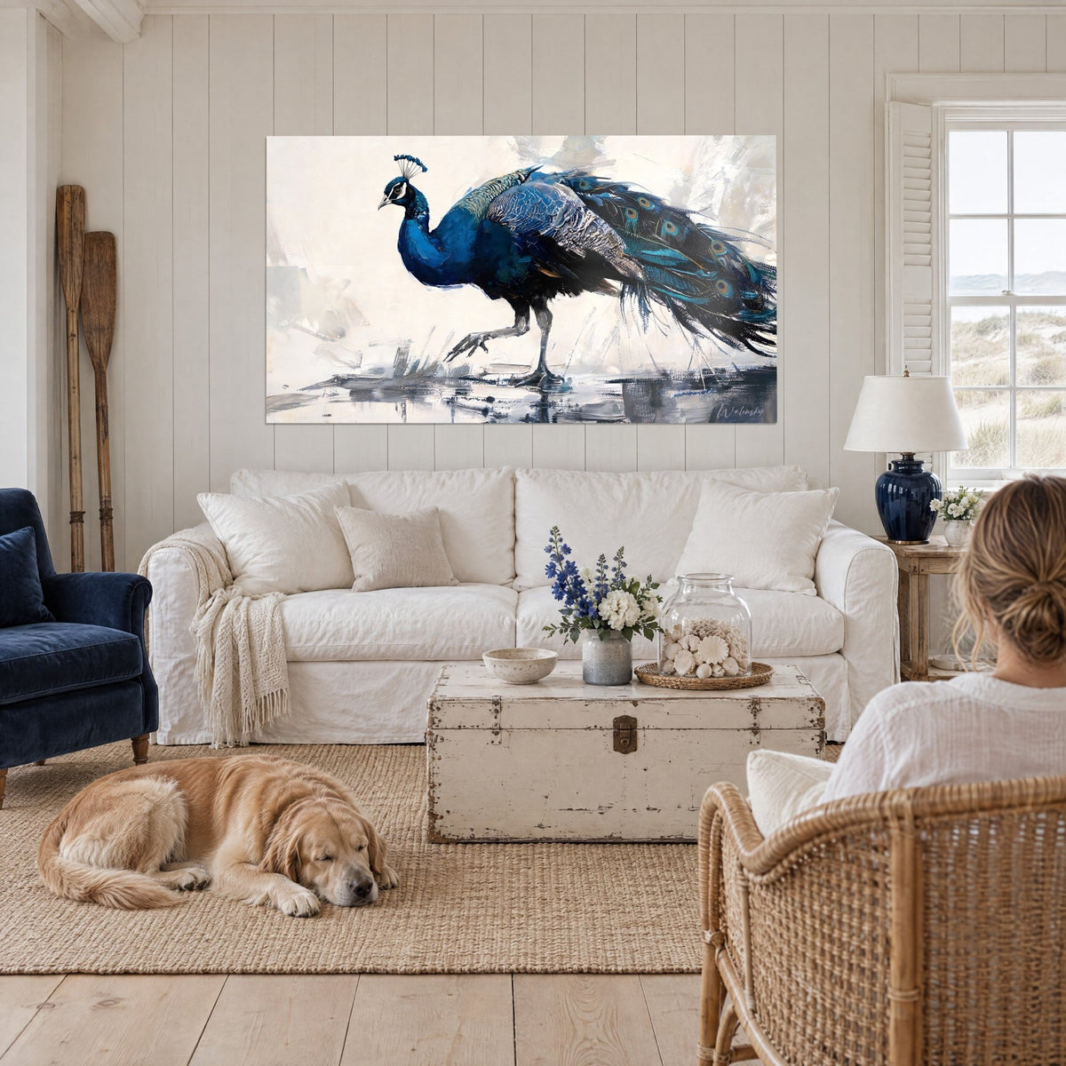 Tableau paon bleu marine à la huppe dressée, queue ocellée turquoise, fond crème, au-dessus d'un canapé dans un salon lumineux