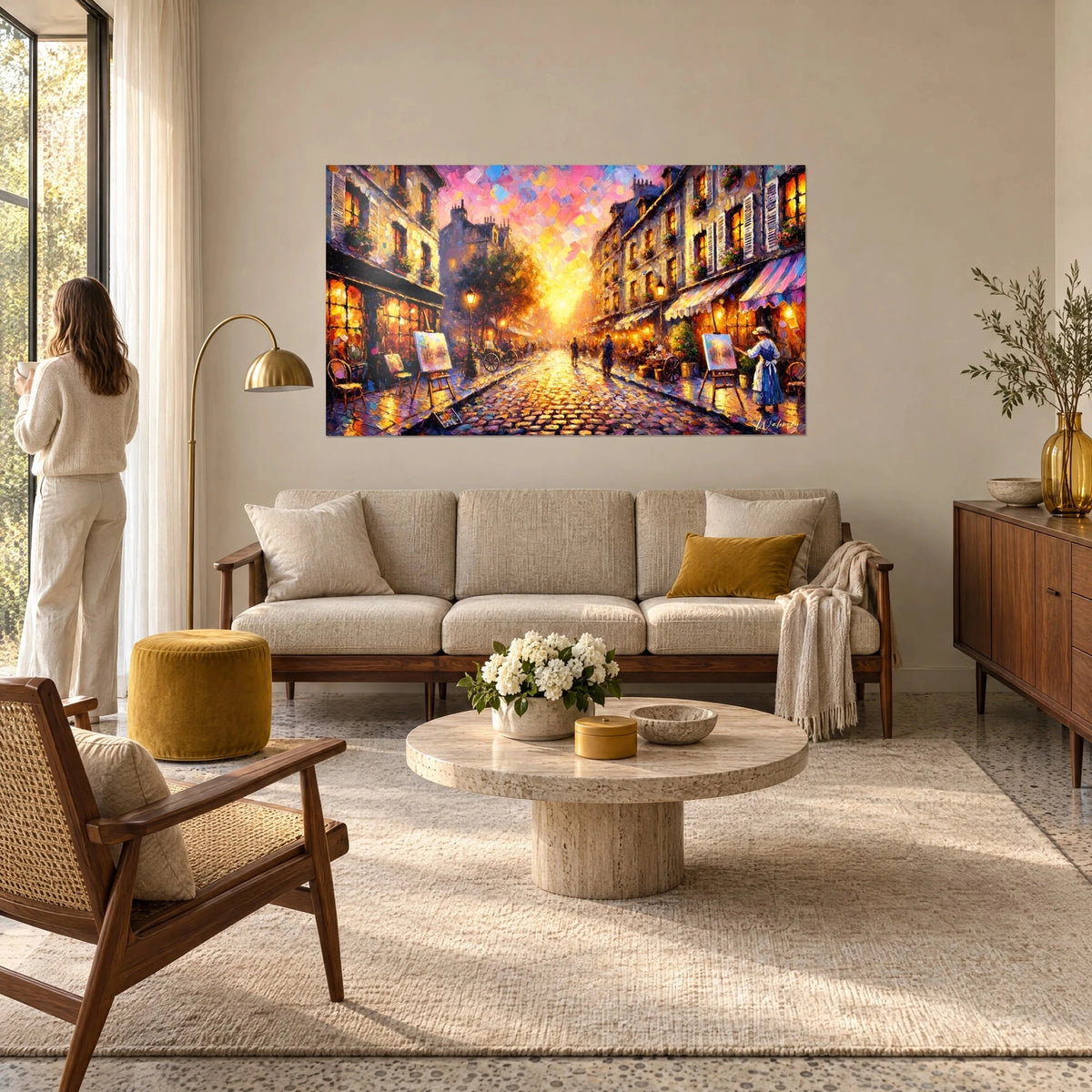 Wall art of a cobbled Paris street ablaze at dusk, pink and orange sky, easels on a terrace, above a sofa in a bright living room