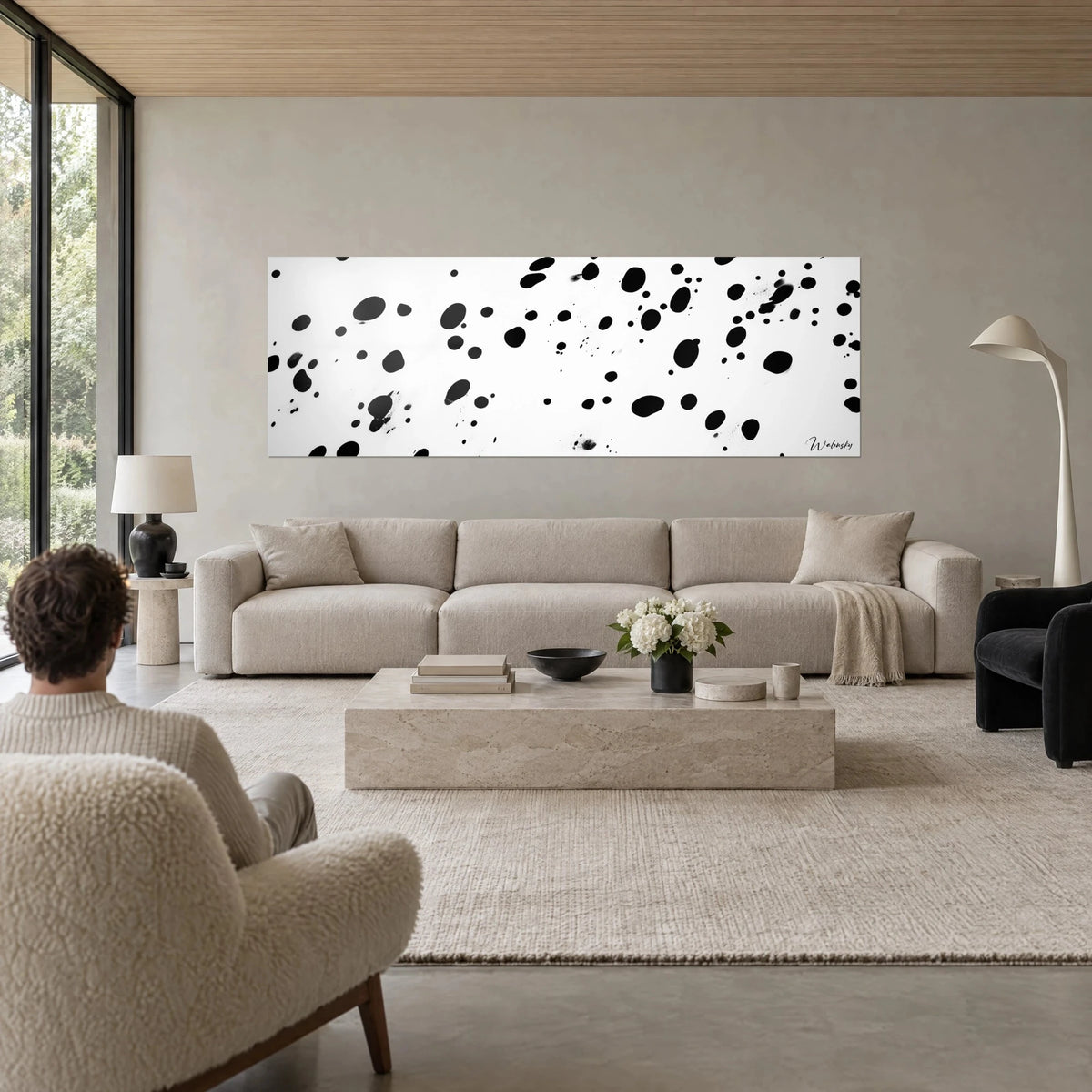 Gemälde mit schwarzen Tintenspritzern auf weißem Grund, abstraktes Panorama über einem Sofa in einem hellen Wohnzimmer