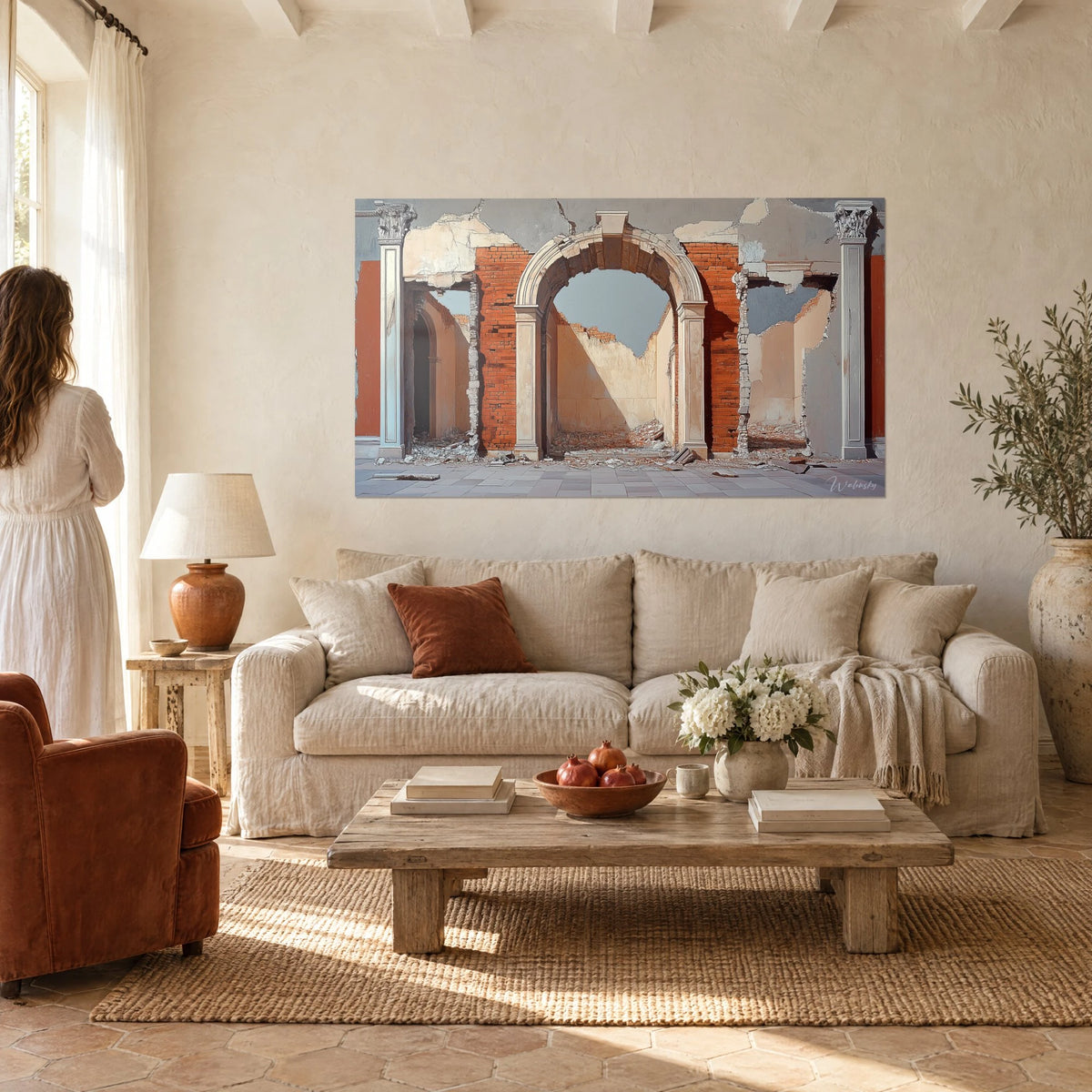 Quadro arco in pietra chiara aperto sul cielo, mattoni rosso mattone e parete crema, donna di spalle, sopra un divano in un soggiorno luminoso