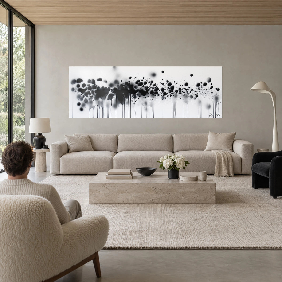 Cuadro de salpicaduras de tinta negra y gris, finos goteos sobre fondo blanco, encima de un sofá en un salón luminoso