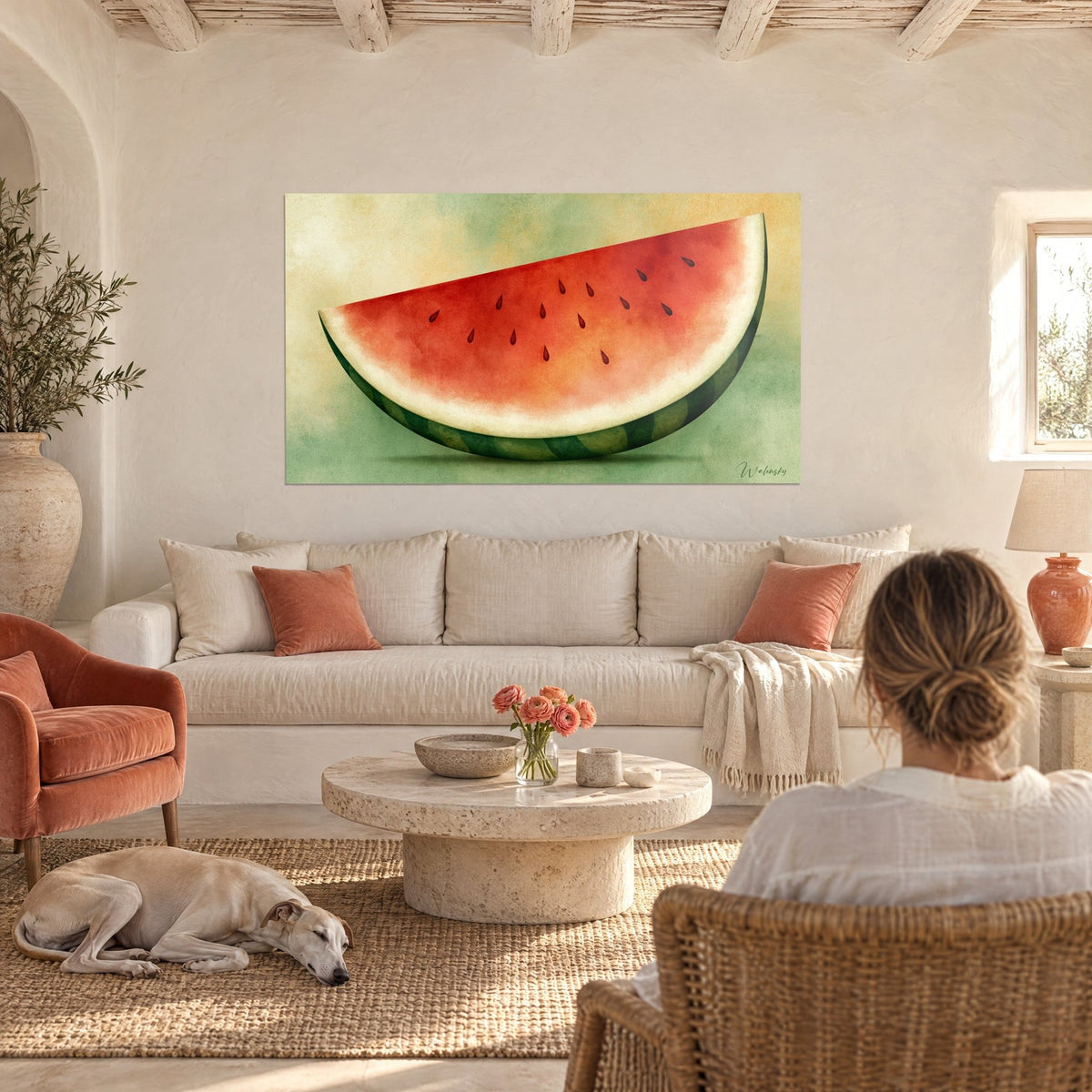 Quadro spicchio di anguria rosso corallo con semi neri su sfondo verde tenue, visto di spalle, sopra un divano in un soggiorno luminoso