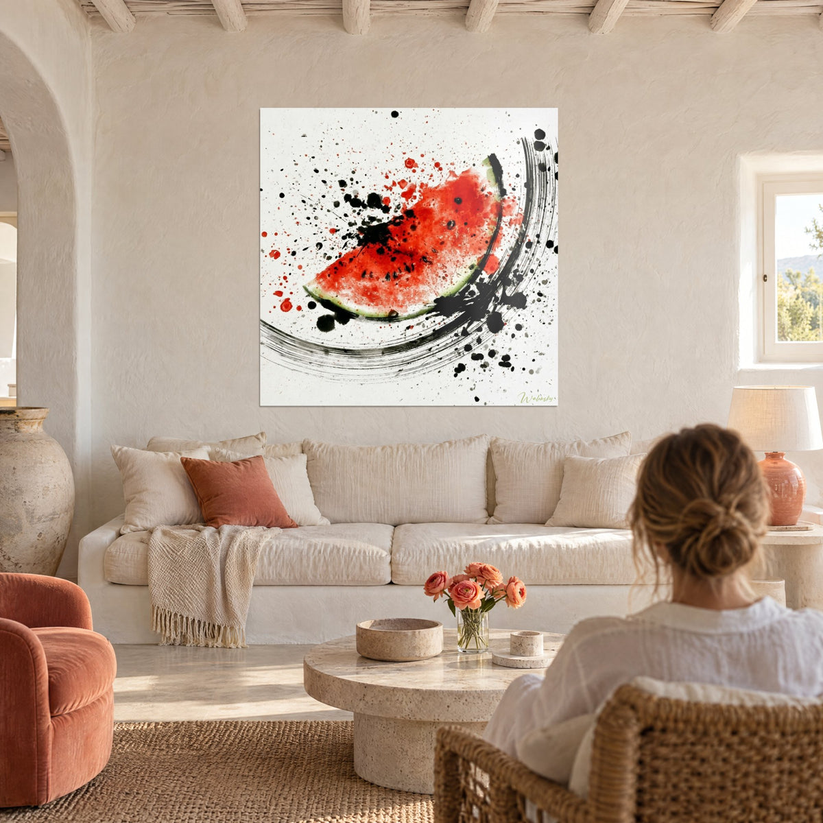 Wall art watermelon quarter in vivid red with black ink splatters, large circular brushstroke, above a sofa in a bright living room