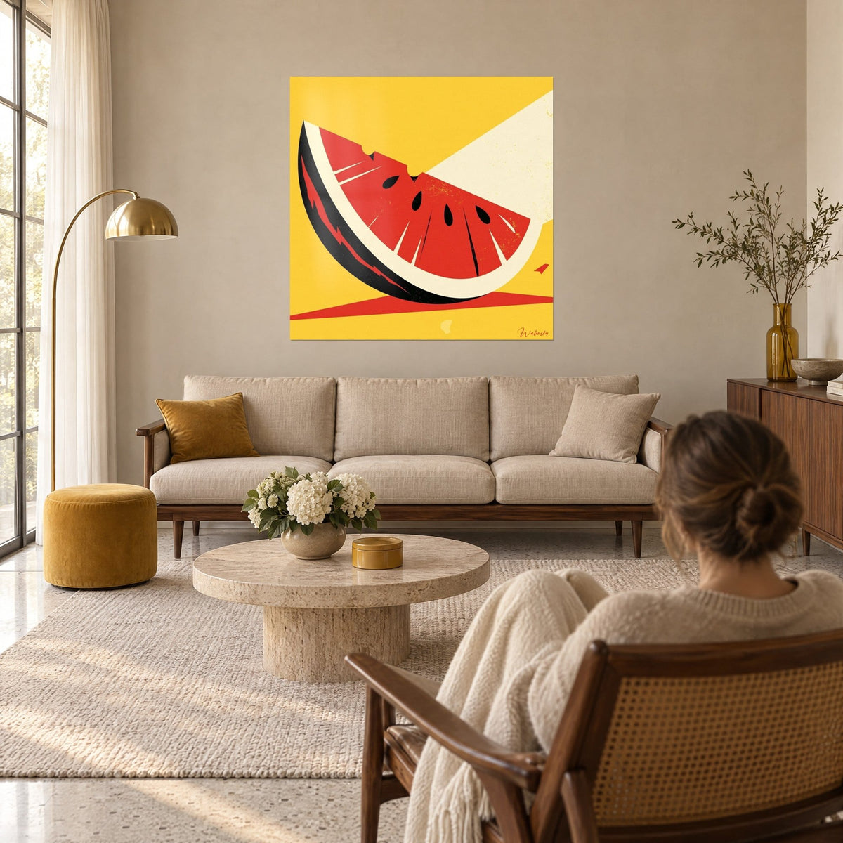 Wall art slice of watermelon in vivid red, black and sunshine-yellow rind, hung above a sofa in a bright living room