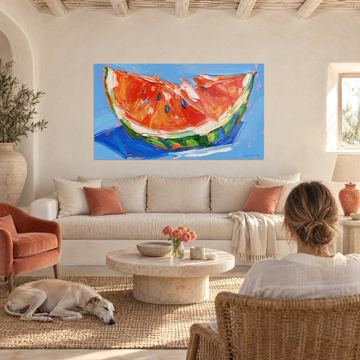 Wall art of an orange and red watermelon wedge painted with a palette knife, sky blue background, indigo seeds, hung above a sofa in a bright living room