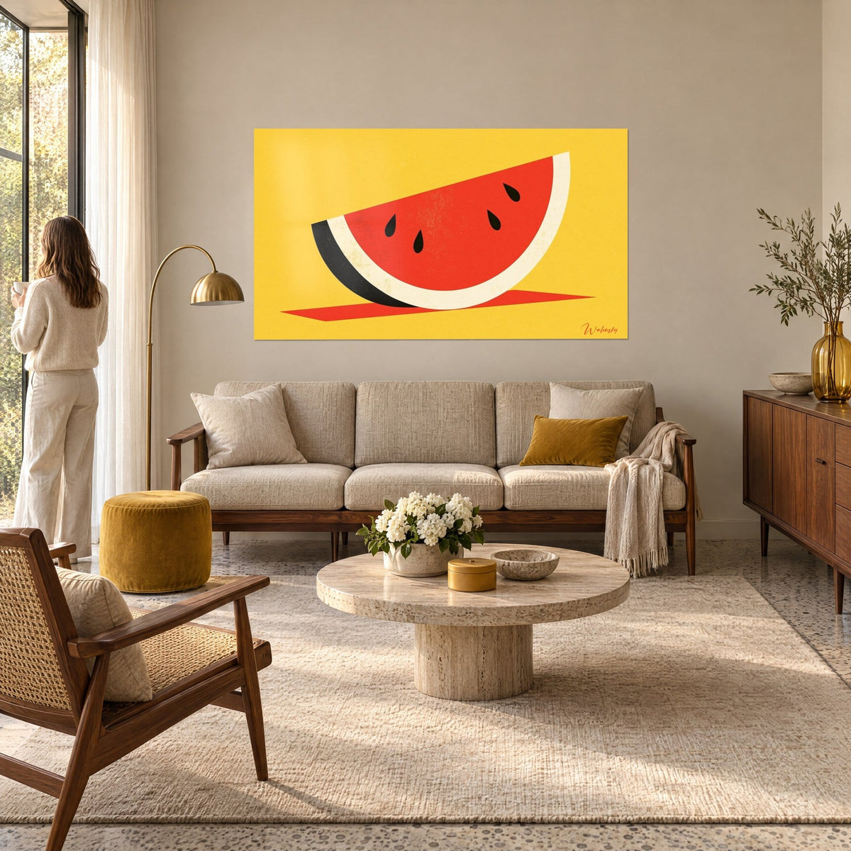 Tableau tranche de pastèque rouge vif, écorce crème et noire sur fond jaune moutarde, au-dessus d'un canapé dans un salon lumineux