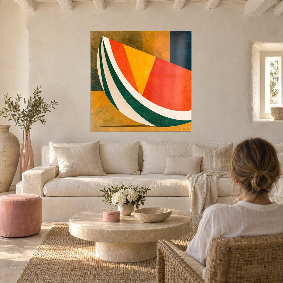 Cuadro sandía geométrica en rojo anaranjado y verde abeto, fondo crema, mujer de espaldas, encima de un sofá en un salón luminoso