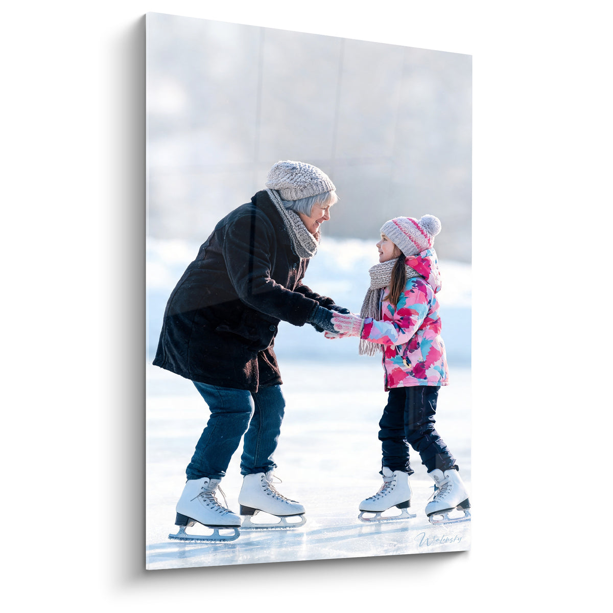 Grand-mère et petite-fille se tenant les mains, patins blancs, manteau anthracite et doudoune rose fuchsia sur glace