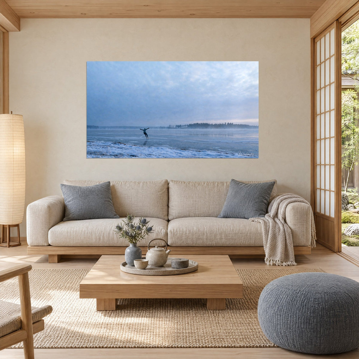 Wall art skater with arms spread wide gliding across a steel-blue frozen lake, pink mist on the horizon, above a sofa in a bright living room