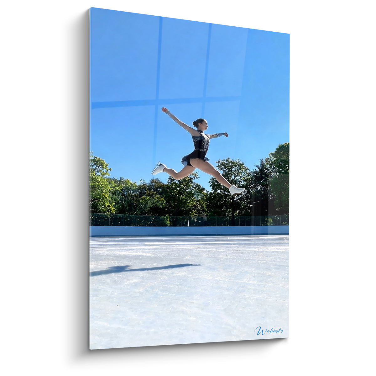 Patineuse en saut suspendu, costume noir scintillant, ciel bleu et glace blanche éclatante