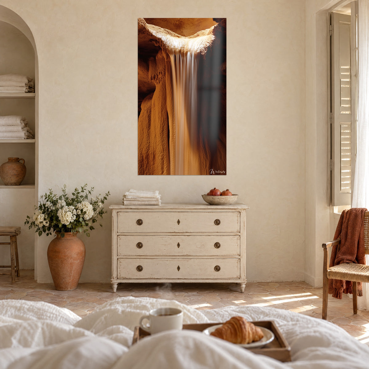 Cuadro Velo de agua blanca cayendo desde un borde de caliza ámbar y óxido, pared enlucida clara, sobre una cama en un dormitorio luminoso