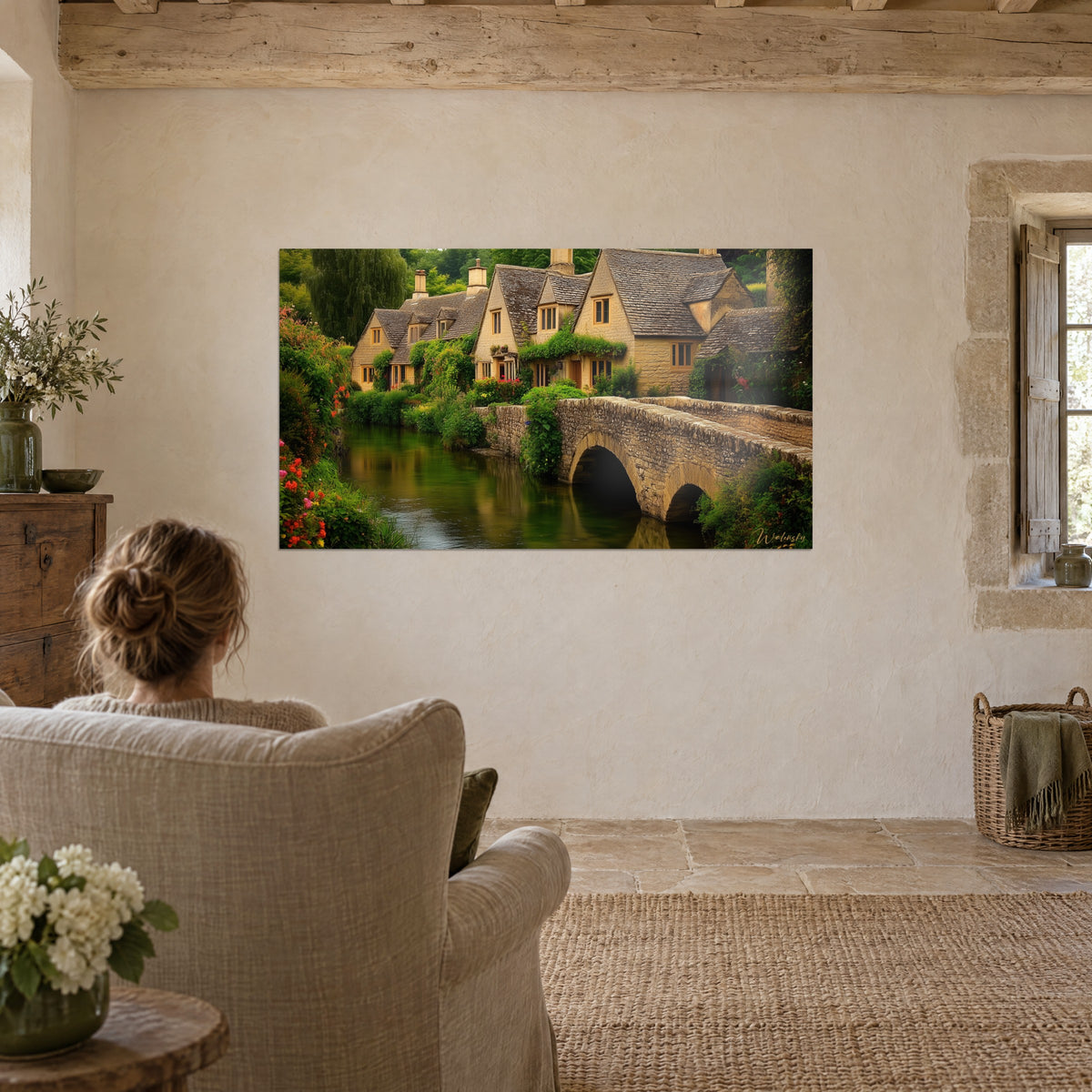 Wall art English village landscape, greyed roofs, honey-yellow walls and flowering garden, facing a beige linen armchair