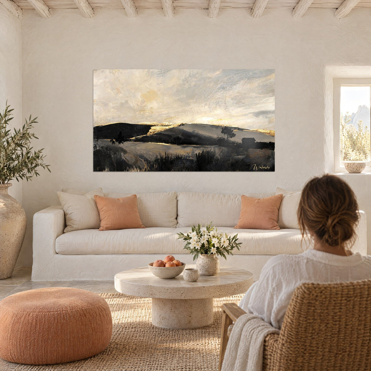 Gemälde mit anthrazitfarbenen Hügeln unter cremefarbenem Himmel, goldene Säume entlang der Kämme, über einem Sofa in einem hellen Wohnzimmer