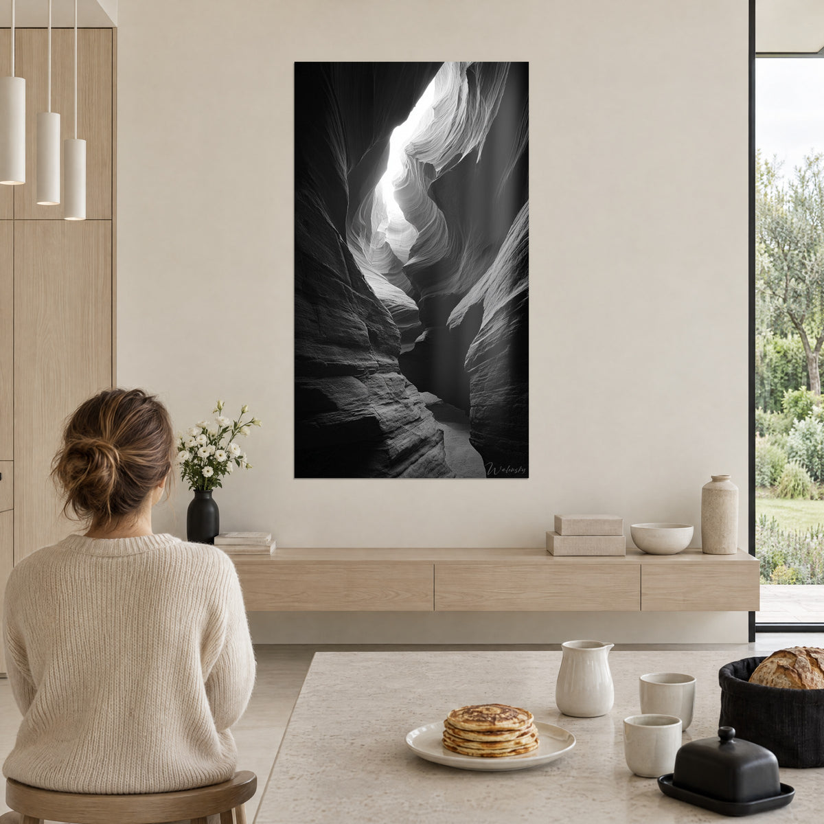 Schilderij canyon van glad gepolijst gesteente, fluwelen zwarten en gestreept zilvergrijs, vrouw met losse knot van achteren, witte muur open naar een tuin