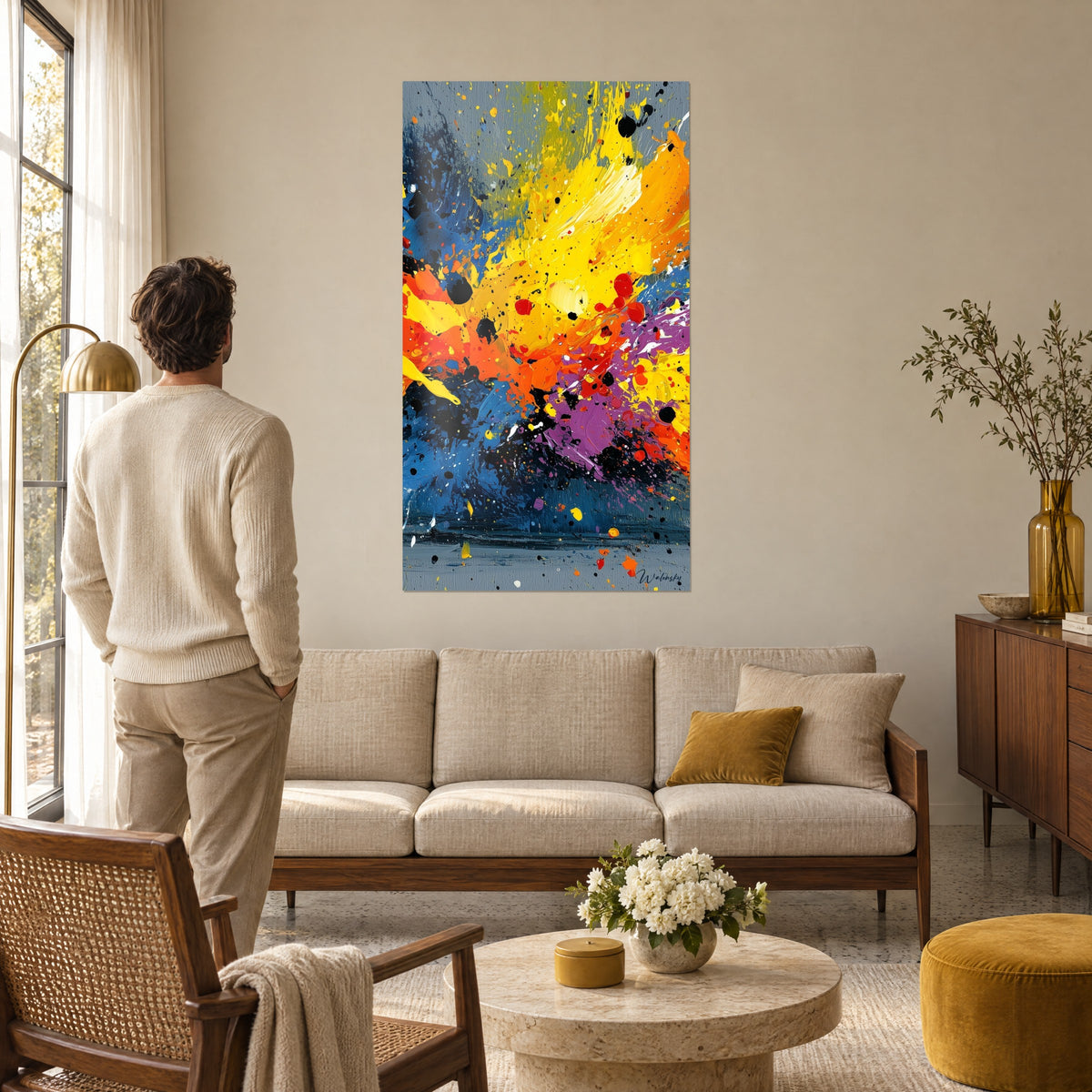 Tableau explosion de peinture jaune citron et bleu cobalt, gouttelettes noires, homme de dos, au-dessus d'un canapé dans un salon lumineux
